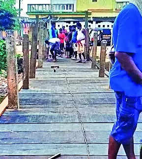 Villagers build bridge with wooden planks over canal