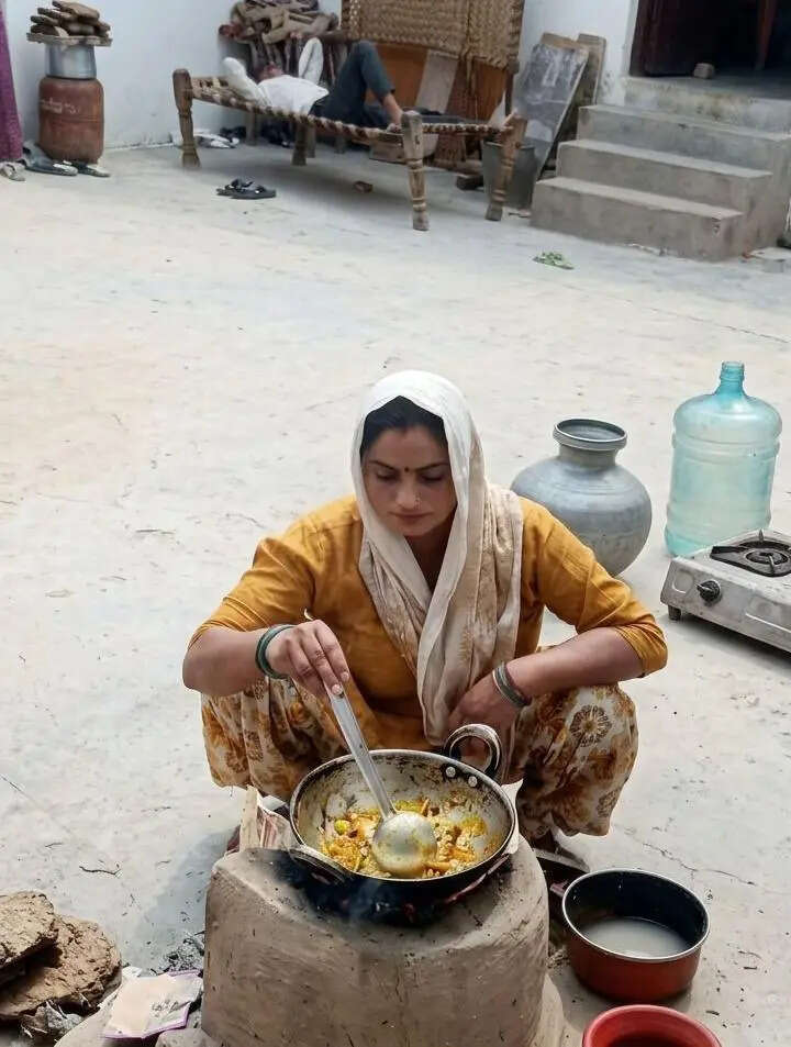 Nisha Devi from Chaprauli village squats over a wood-fired chulha to cook food Nisha Devi from Chaprauli village squats over a wood-fired chulha to cook food