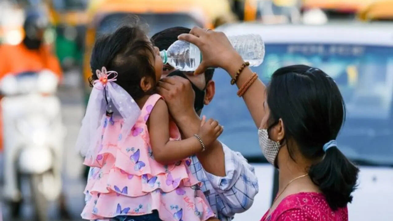 ​Mother helps her young child drink water to cope with the scorching summer heat in the city (Representative image)