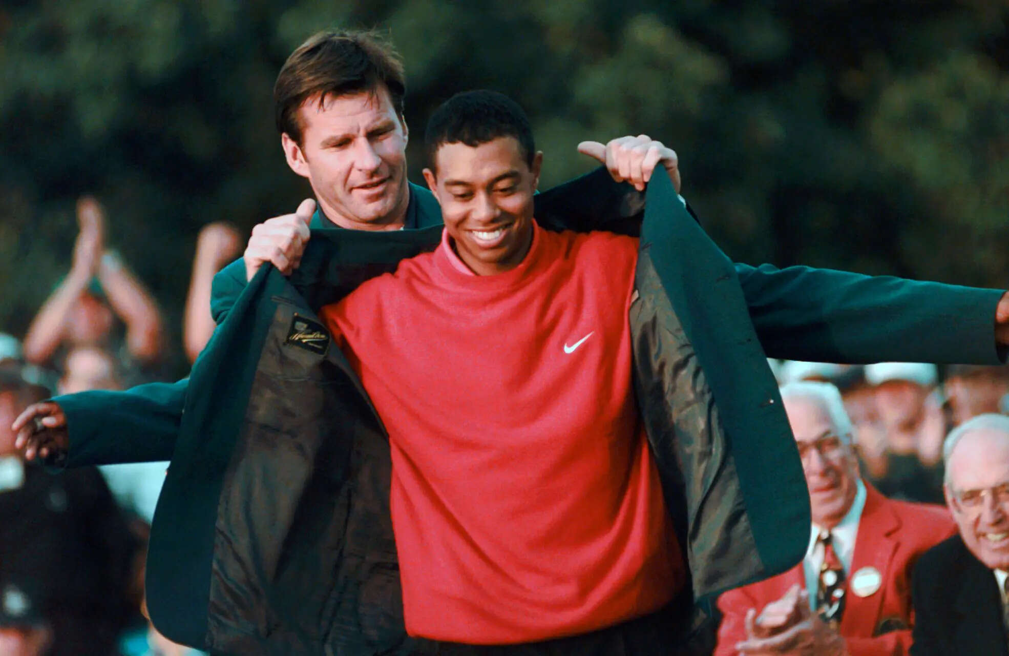 FILE - Masters champion Tiger Woods receives his Green Jacket from last year's winner Nick Faldo, left, at the Augusta National Golf Club, April 13, 1997, in Augusta, Ga. (AP Photo/ Dave Martin, File) A look at Tiger Woods' life as he turns 50, in photos