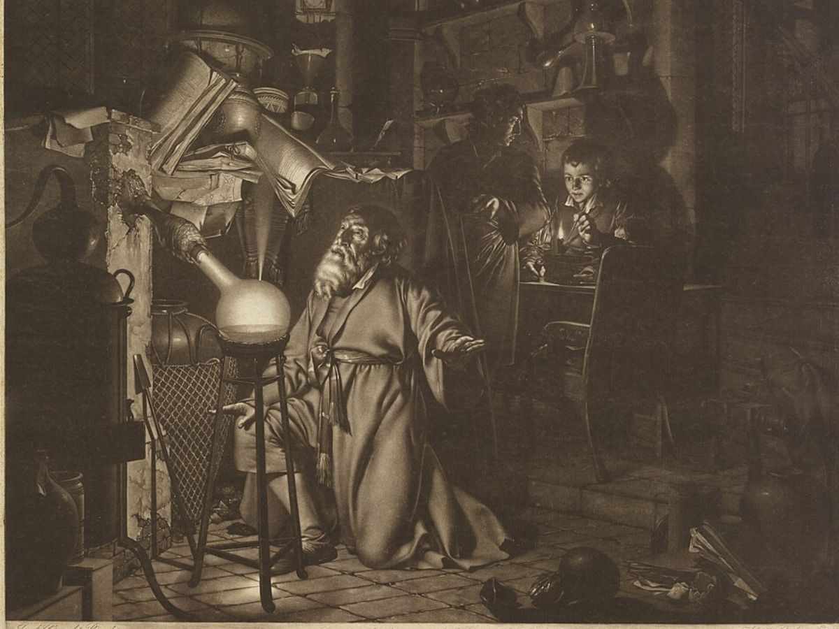 The image illustrates a kneeling alchemist in his laboratory