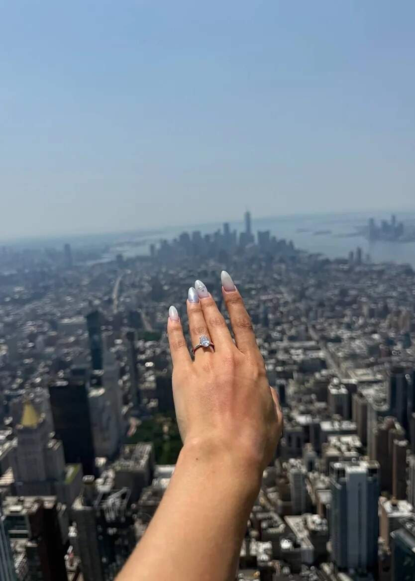 A photo posted by Angela Nikolau that shows a ring on her hand after the proposal atop the spire
