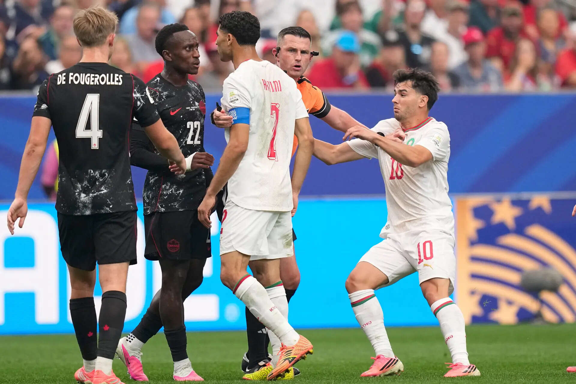 Referee Michael Oliver, of England, holds Morocco's Achraf Hakimi (2) confronting Canada's Richie Laryea (22), during the World Cup round of 16 soccer match between Canada and Morocco in Houston, Saturday, July 4, 2026. (AP Photo/Ashley Landis) Canada Morocco WCup Soccer