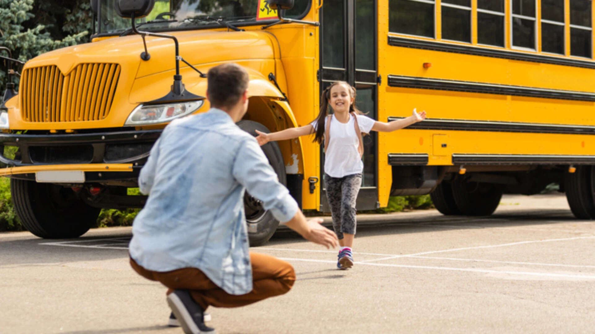 Father meeting little daughter coming out of school bus<br>