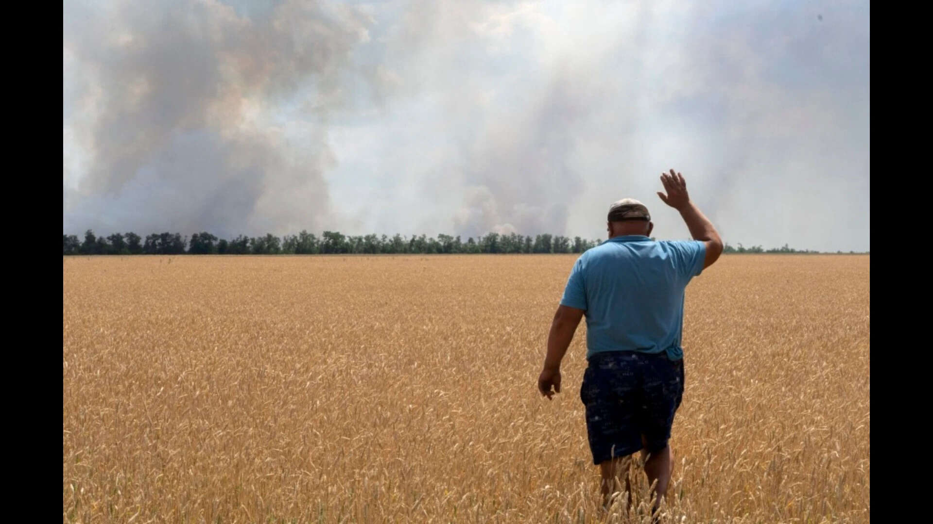 A Ukrainian farmer watches as patches of his wheat fields burn (AP file photo)