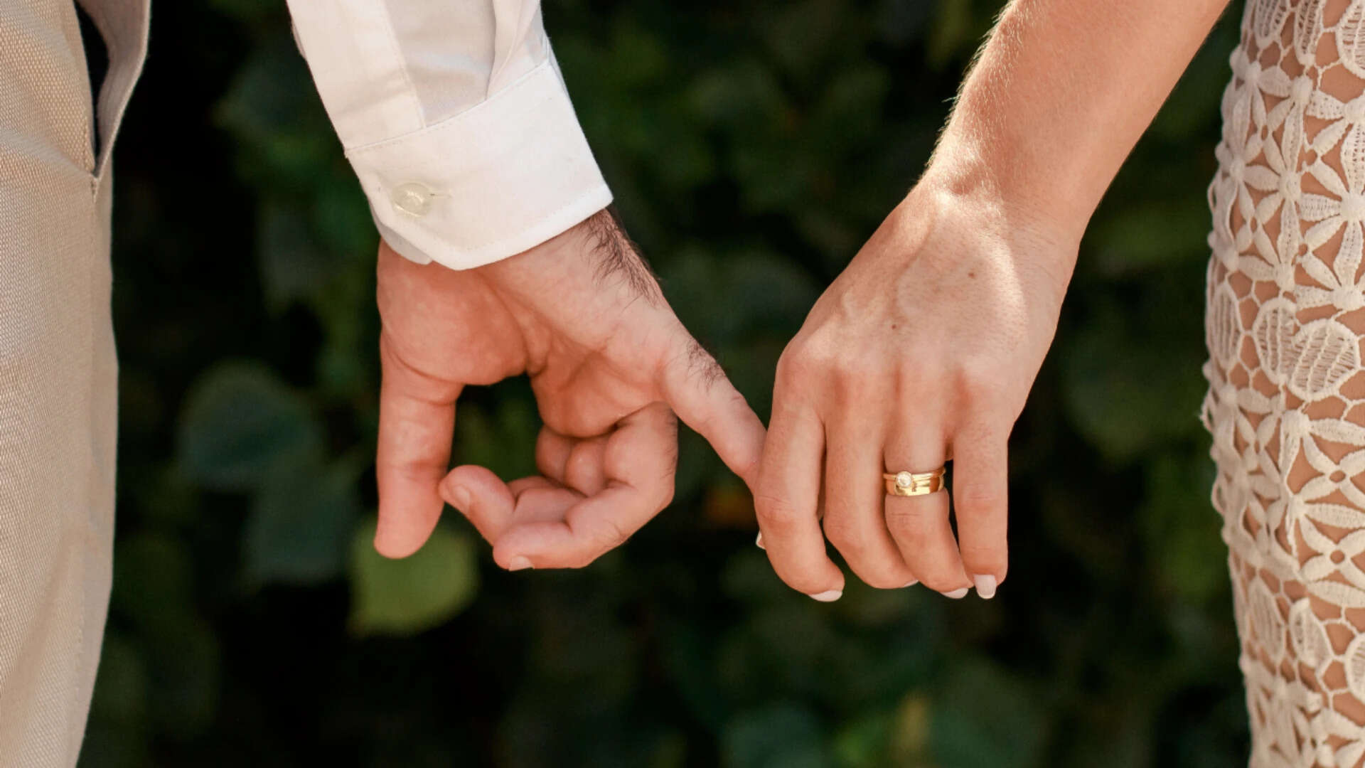 Loving husband and wife with golden rings holding hands<br>