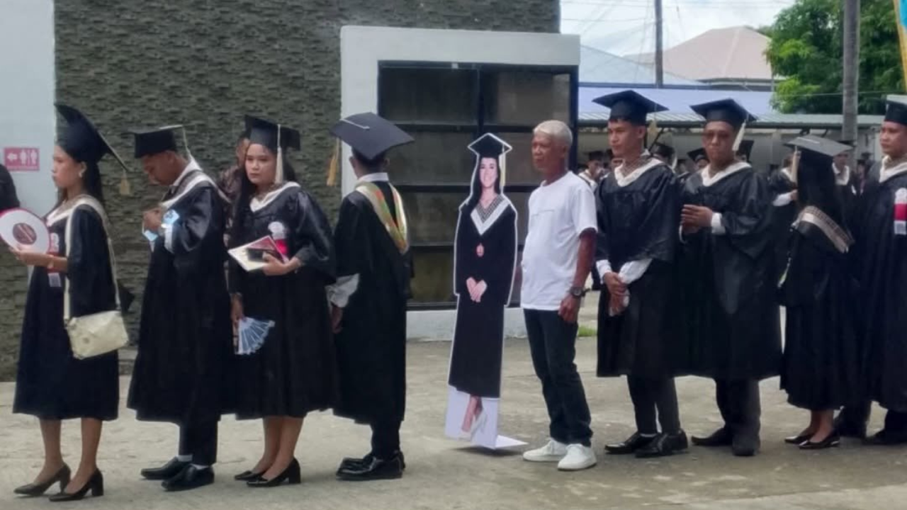 Cesar Cahilig standing in a queue with other graduates, along with his late daughter's cut out