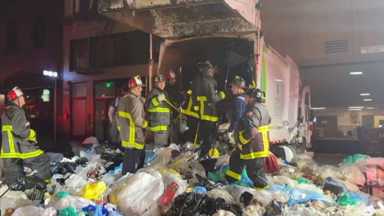 Bystander heard screams from a compacted garbage truck; 25 firefighters rescued a trapped man alive