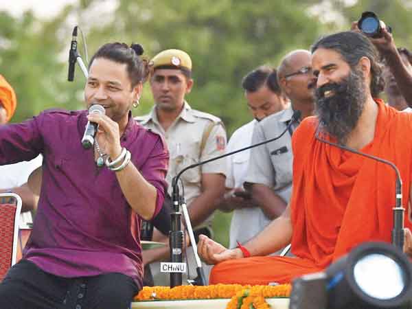 Yoga guru Baba Ramdev looks on as Kailash Kher performs during a yoga camp at Rajpath on Sunday