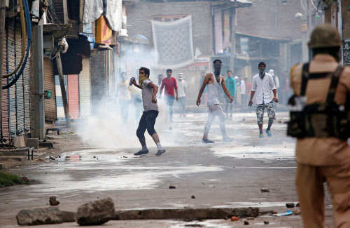 A protester throws back a tear gas shell fired by the police during a protest in Srinagar. (Reuters photo)