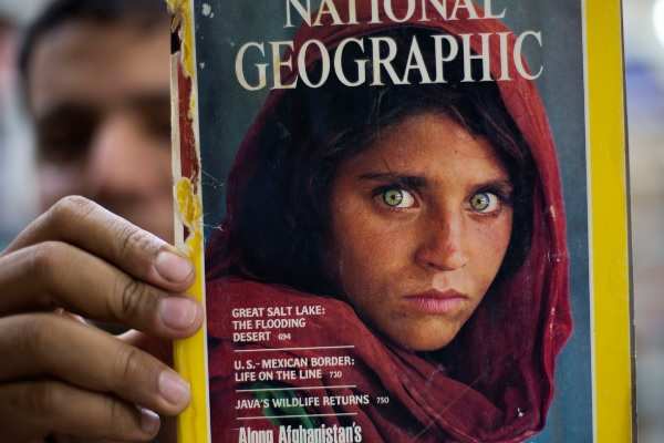A Pakistani bookshop owner holds of a copy of the 1985 National Geographic edition with 'The Afghan Girl' in its cover photo. (AP Photo)