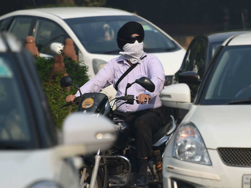 A biker wearing face protection against air pollution rides on the road in New Delhi on October 28. (AFP photo)