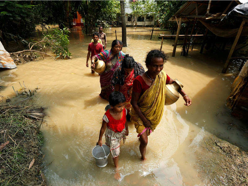 People wade through a flooded road to collect drinking water in Howrah district, West Bengal. (Reuters photo)