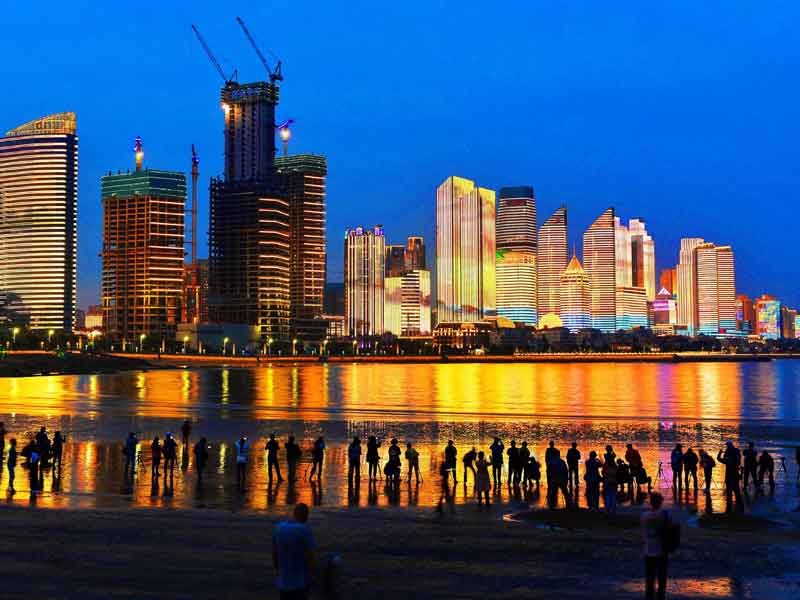 This photo taken on May 26, 2018 shows residents and visitors looking at illuminated buildings in Qingdao in China's eastern Shandong province. This year's summit of Shanghai Cooperation Organization (SCO) will be held in the city of Qingdao in June. (AFP photo)