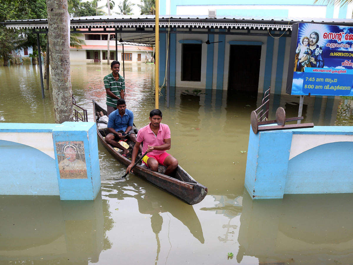 Men paddle their boat through the lawns of a partially submerged church at Kuttanad in Alleppey district. (Reuters Photo)