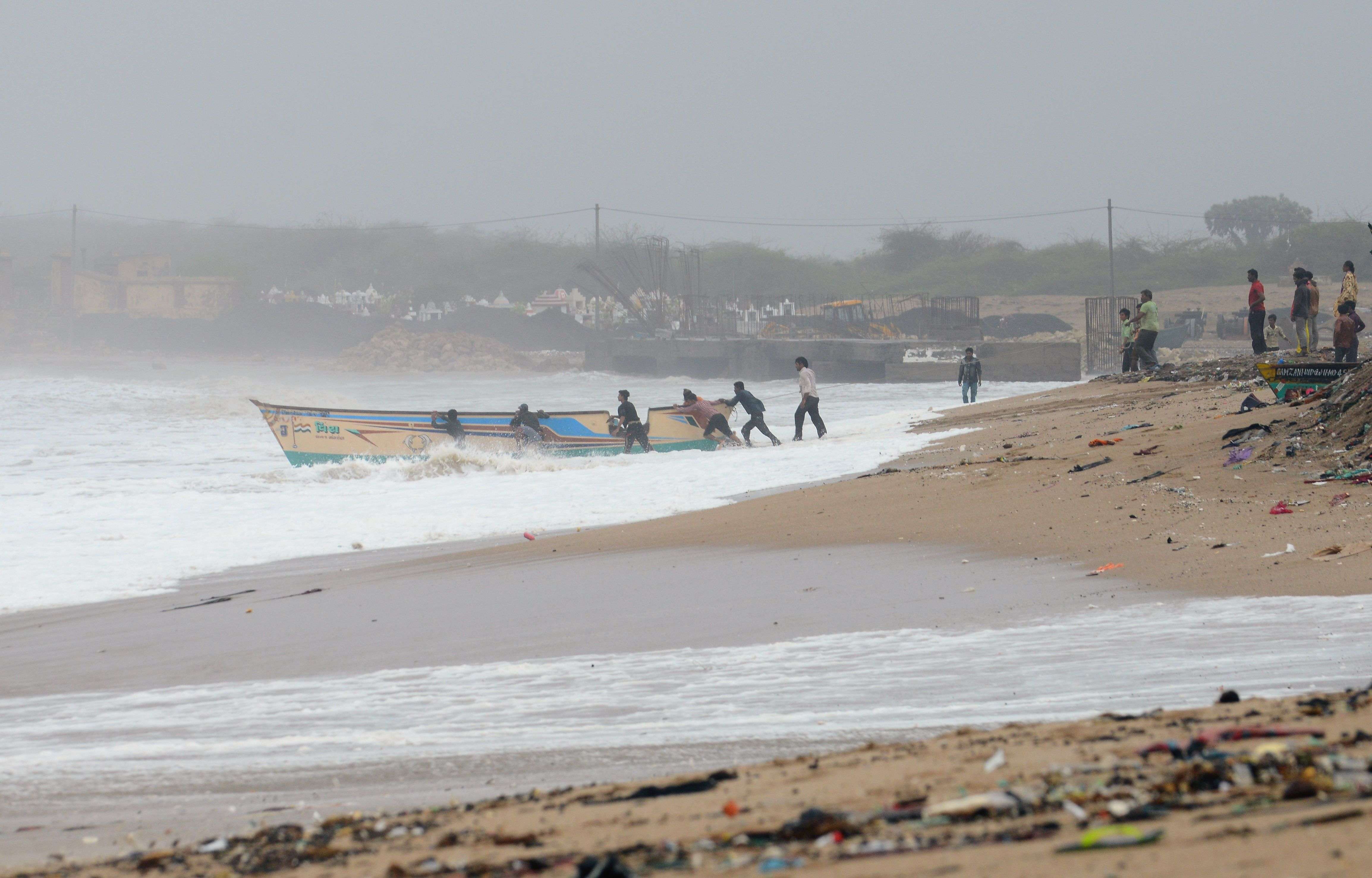 Indian fishermen try to save a boat from being washed on the outskirts of Veraval, 400km from Ahmedabad. (AFP photo)