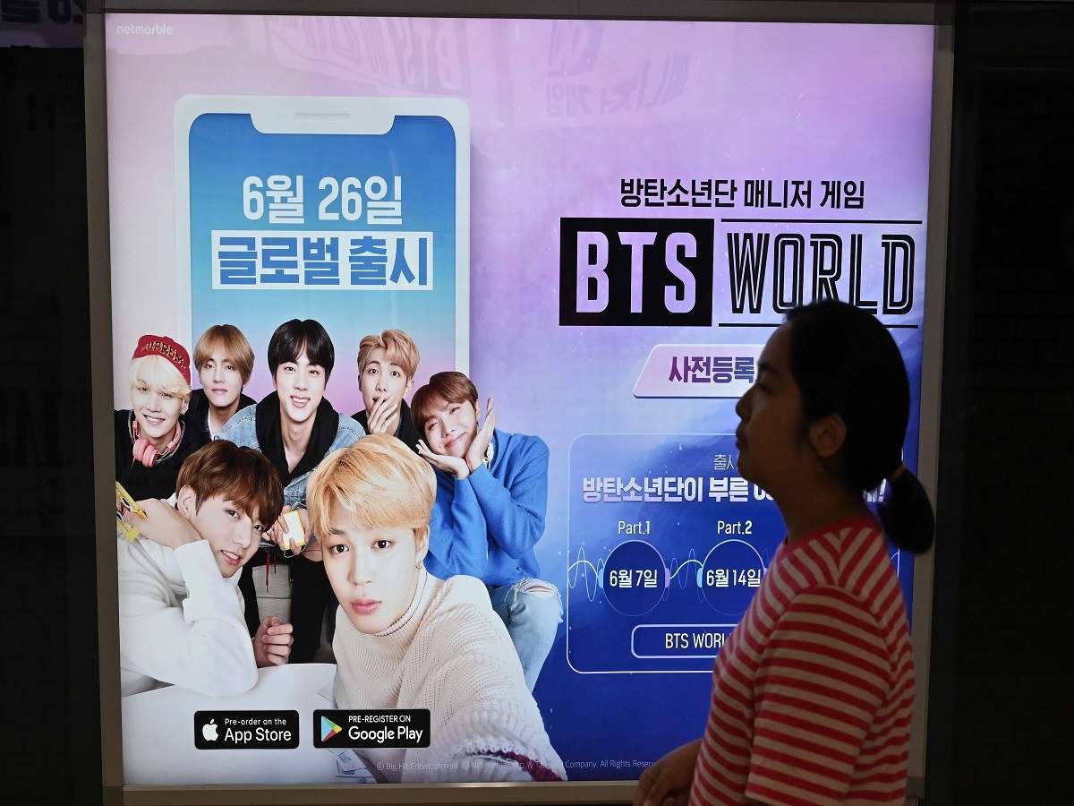 A woman walks past an advertisement of 'BTS World' at a subway station in Seoul (AFP)