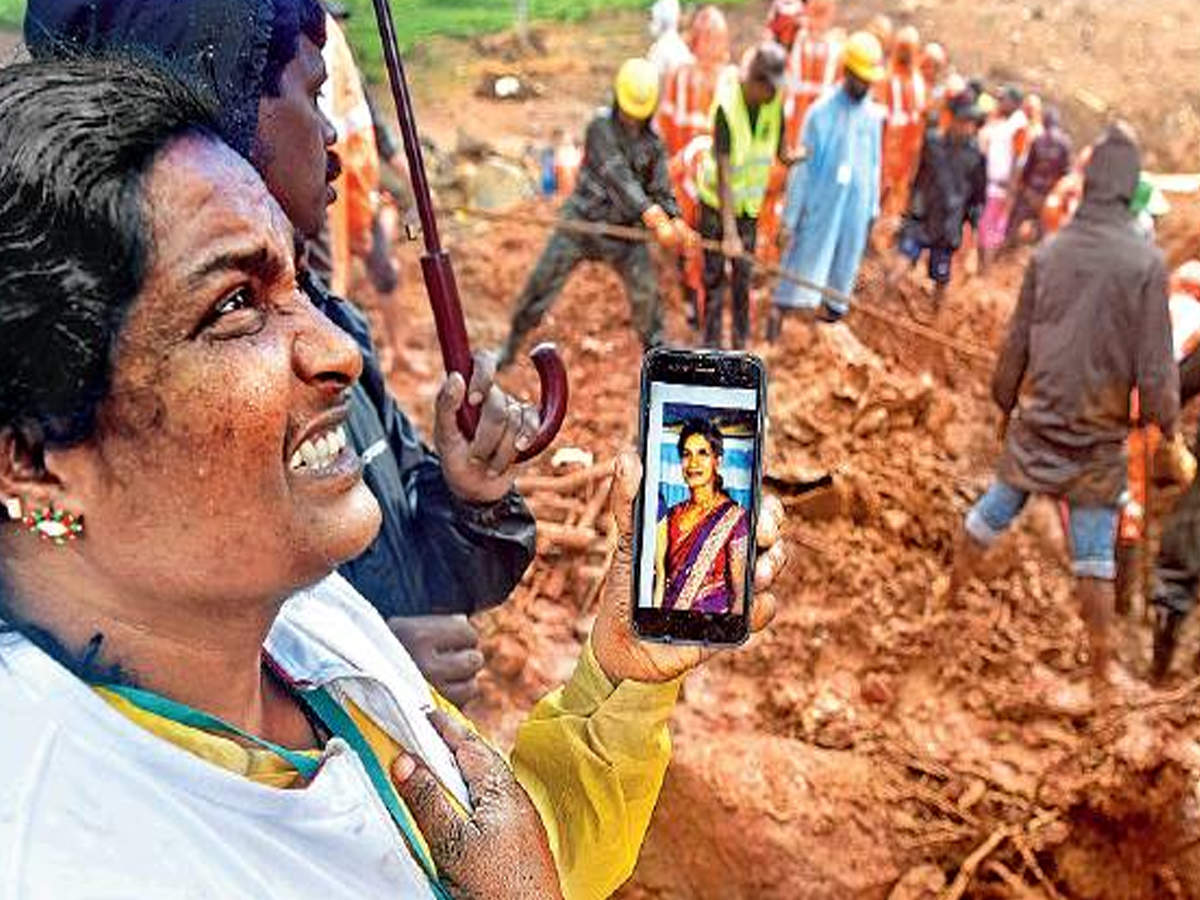  A local resident shows the photograph of a woman who went missing in the landslide to members of the search and rescue team at Puthumala in Wayanad on Sunday