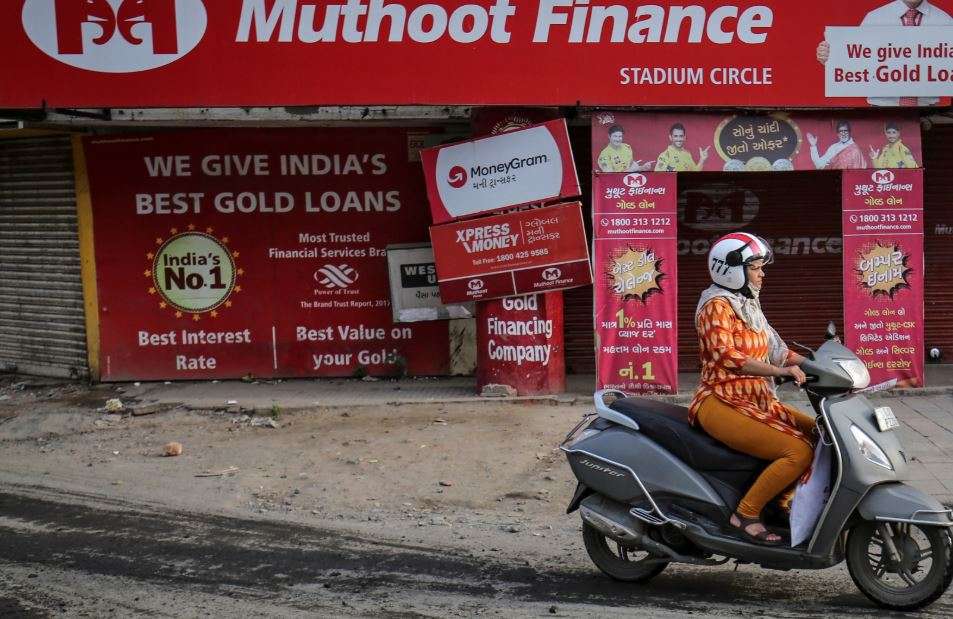 A woman rides her scooter past a Muthoot Finance branch (Reuters)