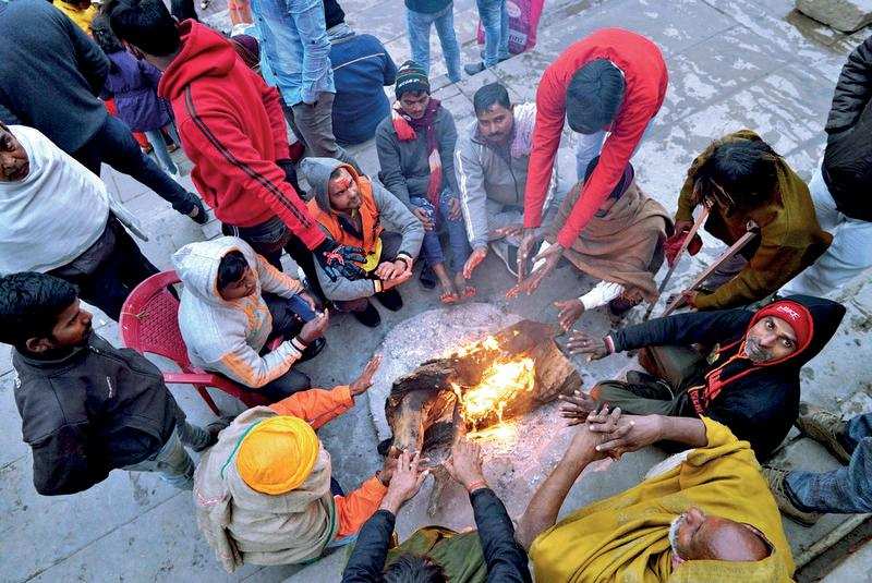 one winter day:  Local residents keep themselves warm by lighting a bonfire and a foreign national braves the cold to attend Ganga aarti at Dashashwamedh Ghat in Varanasi on Monday