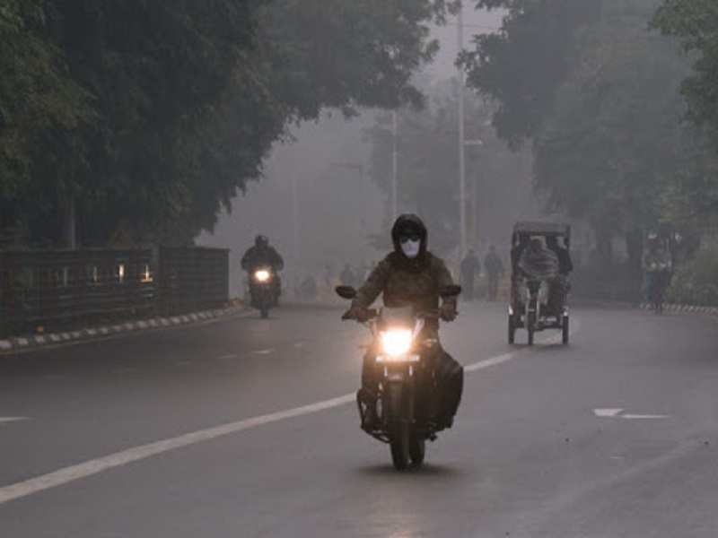 A man rides a bike covering his face on a cold winter day, in New Delhi. (ANI photo)