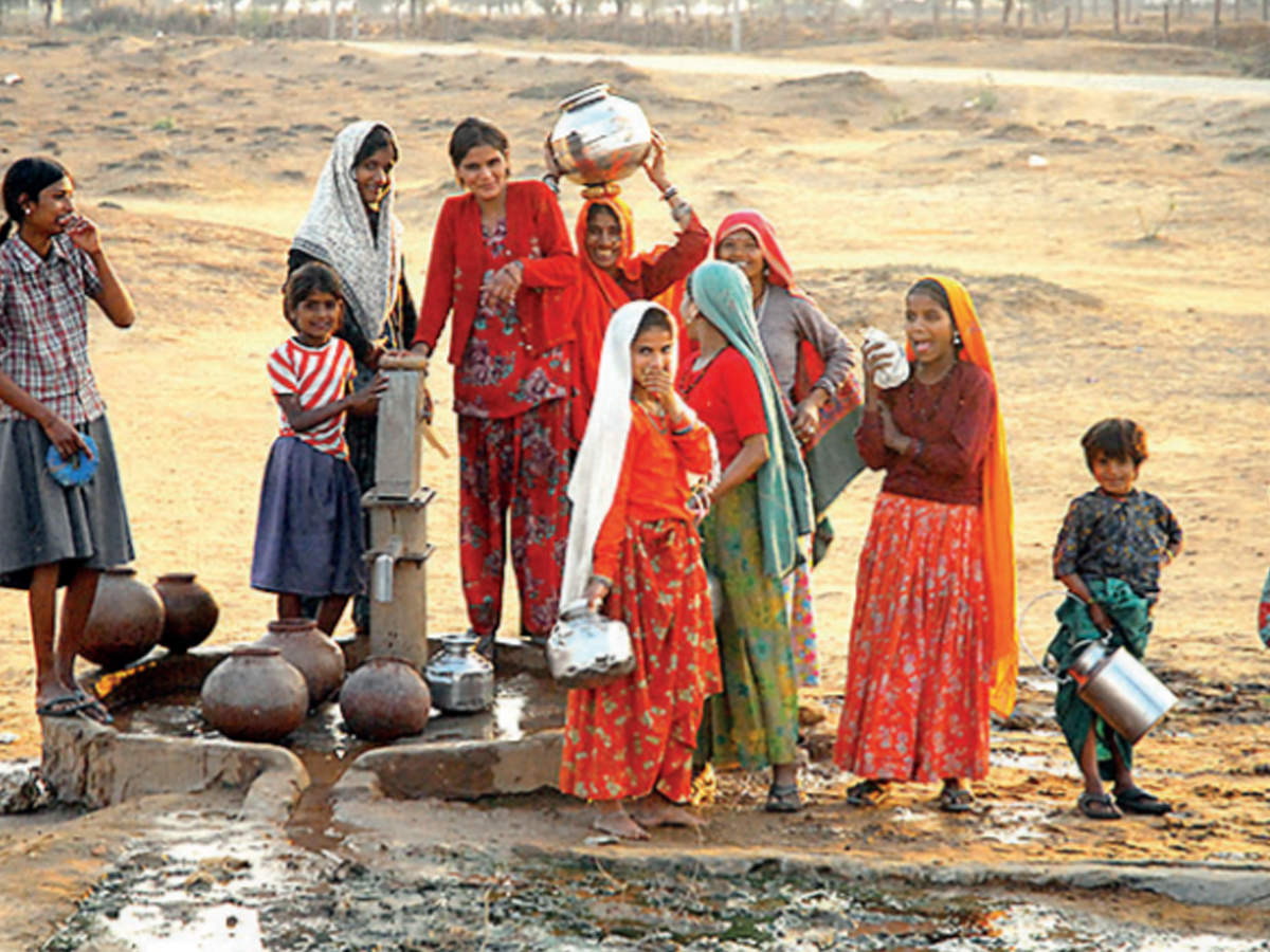 Women wait to collect water in a village