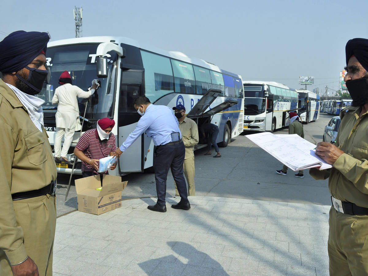 Patiala: Security personnel stand guard as workers clean the Volvo buses meant to bring back pilgrims stranded in Maharashtra. 