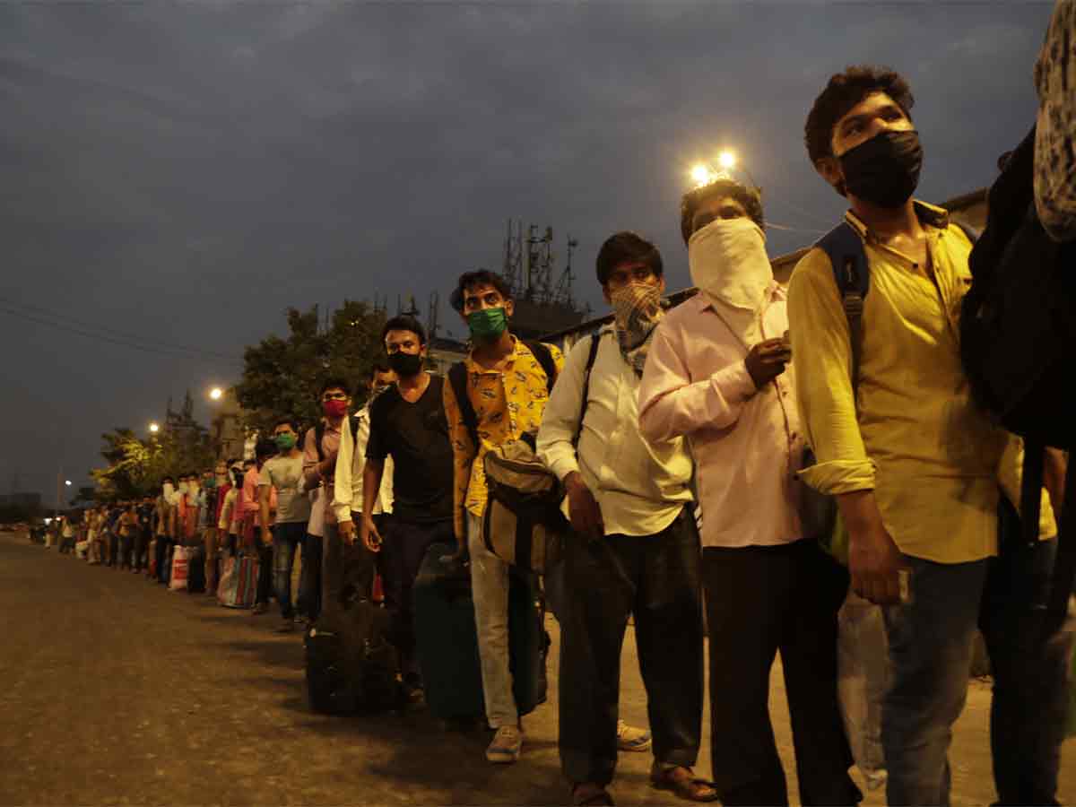 Migrant workers from other states line up to board buses for their onward journey by train to their destination, at Dharavi on May 15, 2020.  (AP Photo)