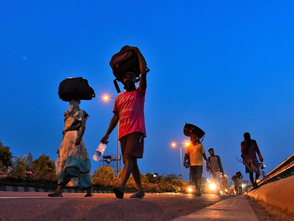 Migrant labourers along with families and luggages on head walk along the road. (TOI photo)