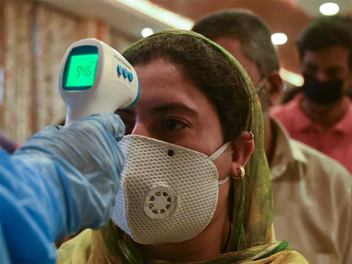 A doctor checks the body temperature of migrant workers. (AFP Photo)