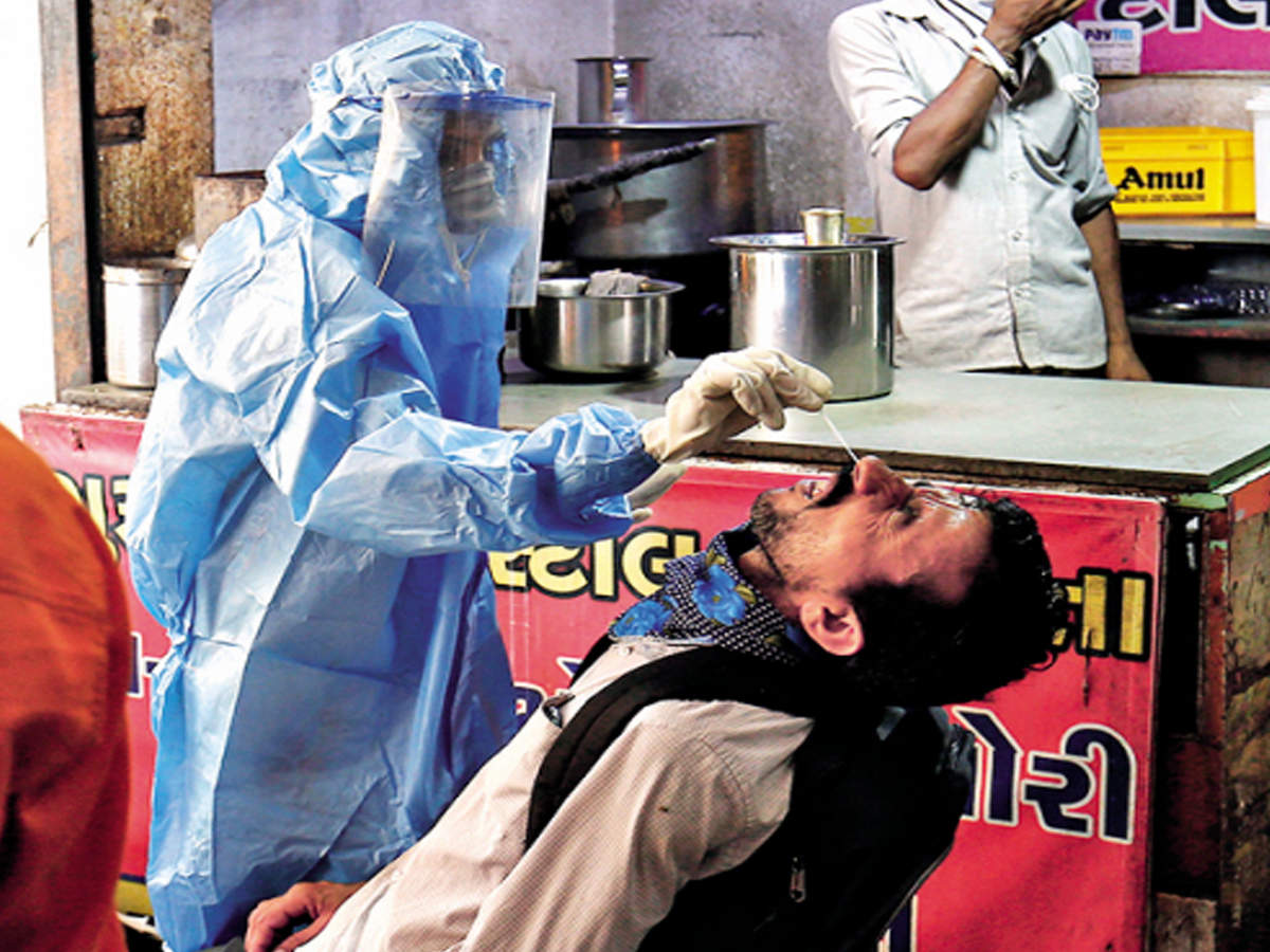 A health worker takes a swab sample from a man outside a tea stall in Ahmedabad on Wednesday