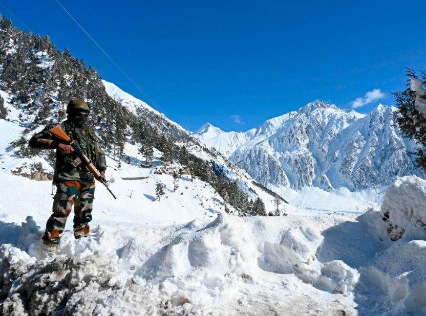 An Indian army soldier stands on a snow covered road after snowfall near Zojila mountain pass (AFP)