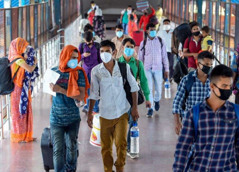 Passengers, wearing face masks, arrive to board a train at New Delhi Railway Station (PTI)