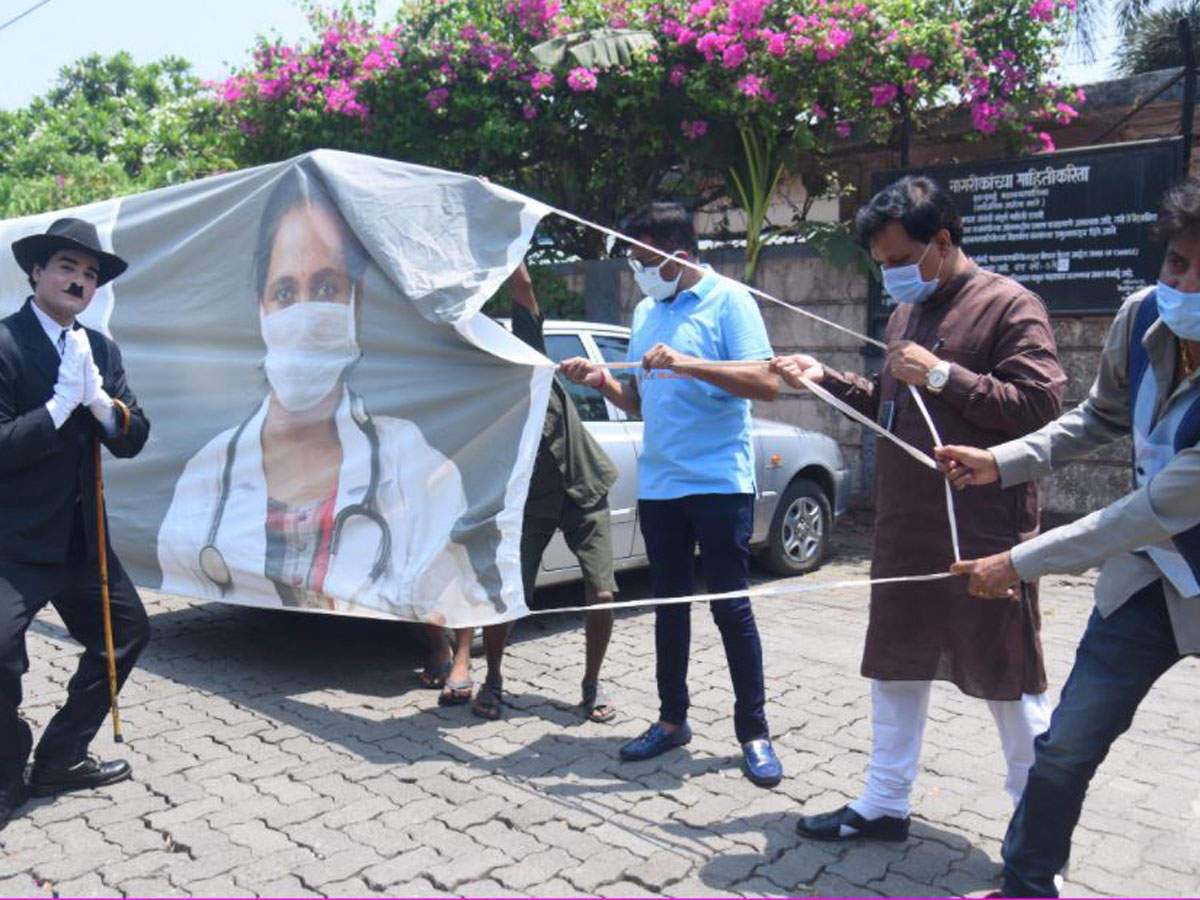 A man dresses up as Charlie Chaplin, as people hold a 55-feet long mask banner to create awareness of the preventive measure against the Covid-19, amid the rise in covid-19 cases across the country at Goregaon, in Mumbai, Friday. PTI 