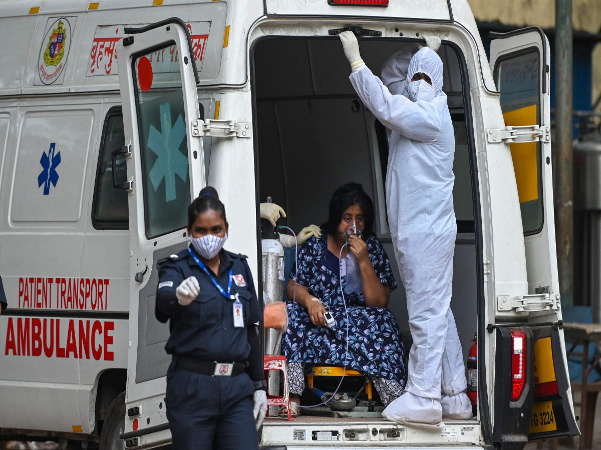 A health worker wearing PPE stands with a patient inside an ambulance outside a hospital in Mumbai, as India records more than 3 lakh daily cases for two days in a row. (Credit: AFP)