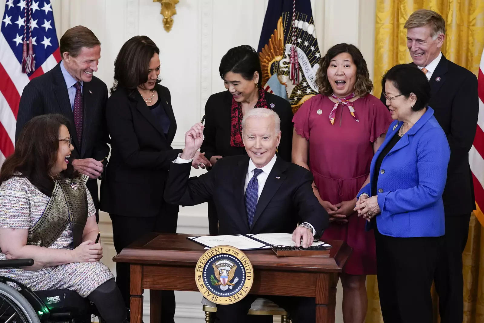 President Joe Biden hands out a pen after signing the Covid-19 Hate Crimes Act, in the East Room of the White House.