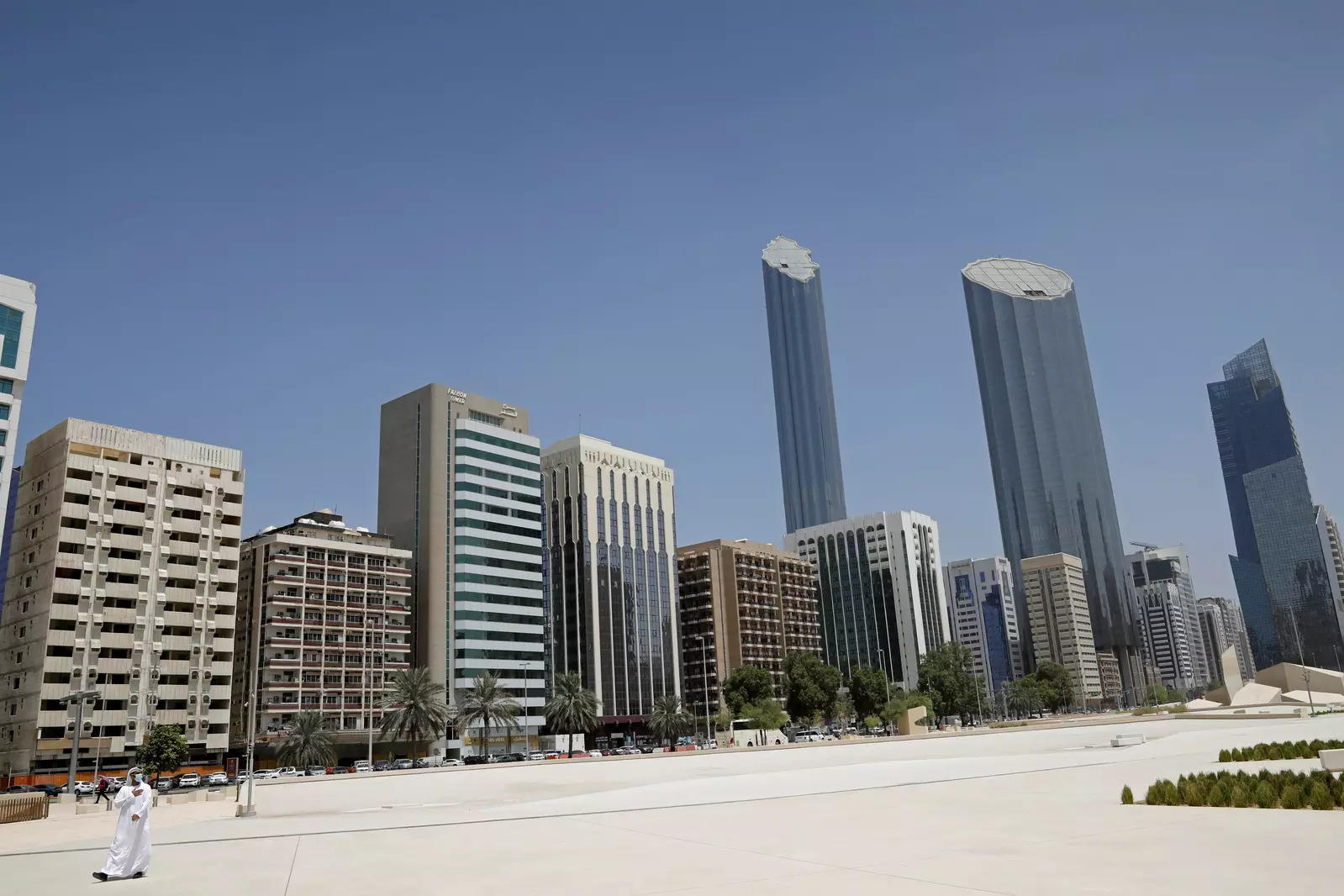 An Emirati man wears a protective mask as he walks past buildings in Abu Dhabi United Arab Emirates 