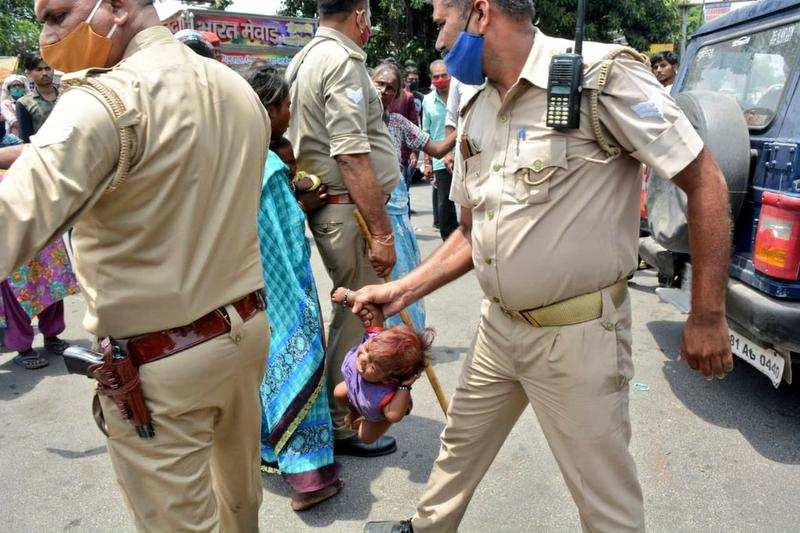 While removing the families from the road, a policeman lifted an infant with its hand