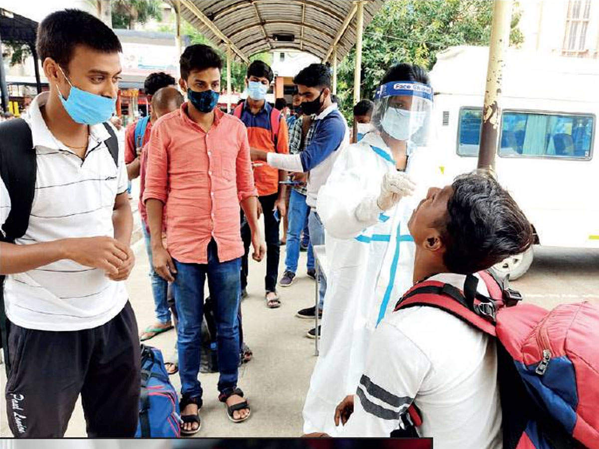 Health staff collect swab samples from travellers at a railway station in Bengaluru