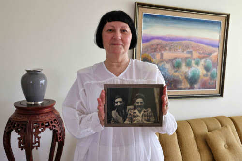 Shoshana Greenberg, 74, the daughter of a Holocaust survivor, poses for a picture holding a portrait of her parents. For Shoshana, the new law making its way through the Polish parliament means abandoning any hope of compensation for the properties taken from her family during World War II. (Photo credit: AFP)