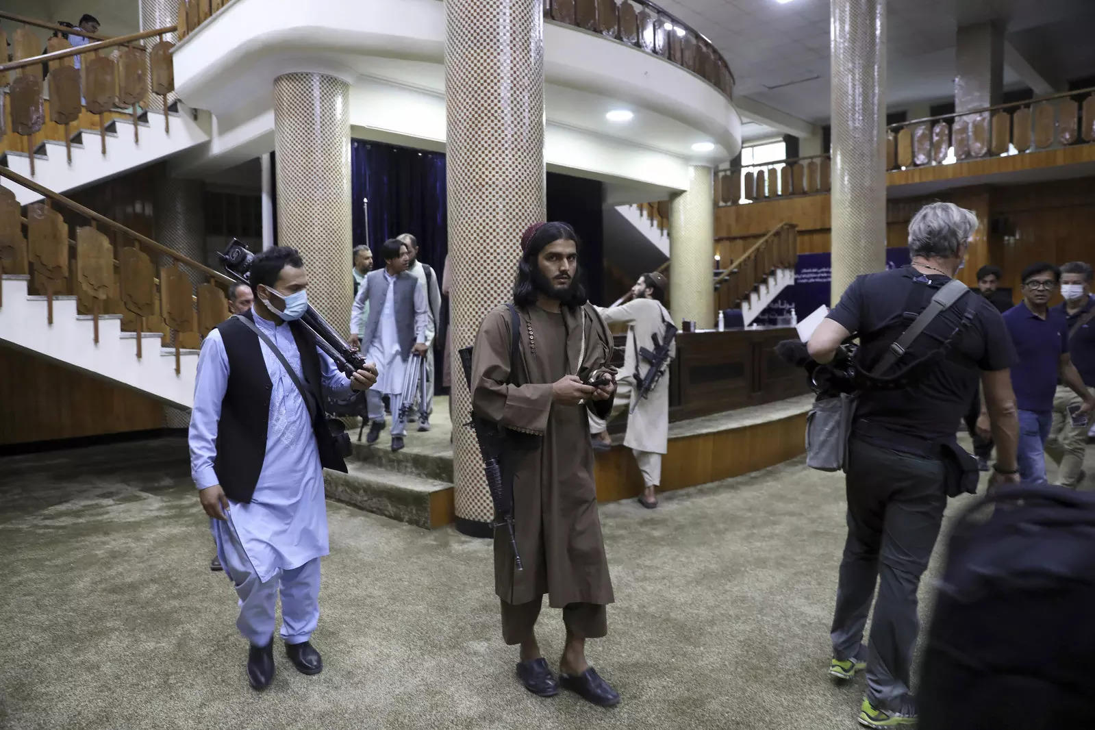 Taliban fighters stand guard before the Taliban spokesman Zabihullah Mujahid arrives for his first news conference in Kabul