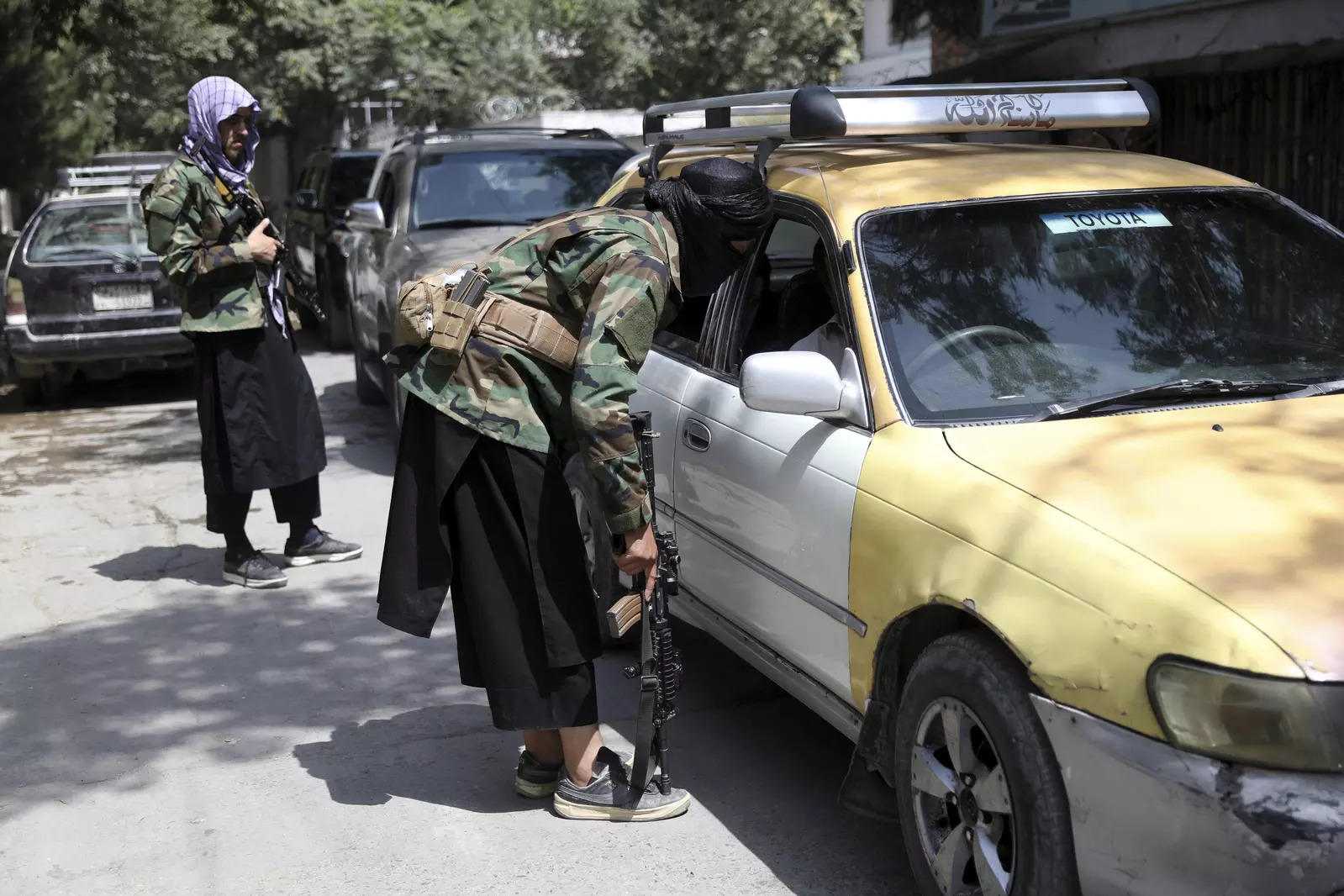 Taliban fighters search a vehicle at a checkpoint on the road in the Wazir Akbar Khan neighborhood in the city of Kabul 