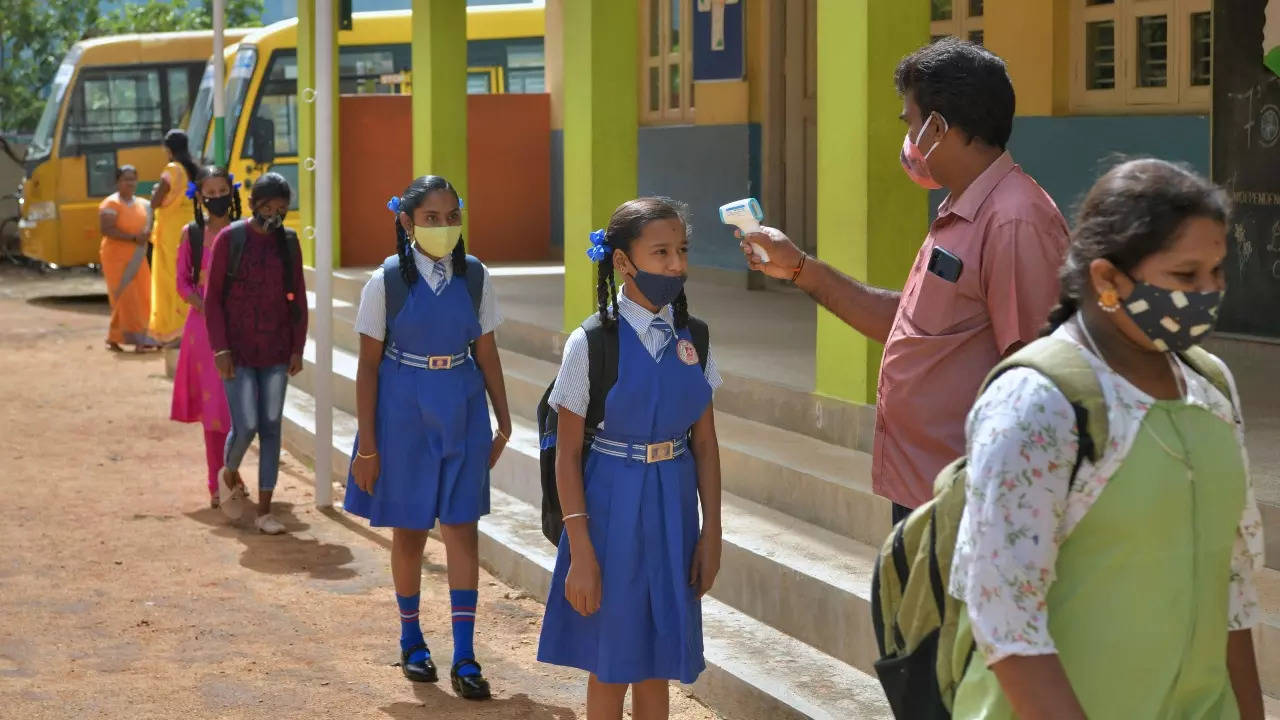 A teacher checks the body temperature of students upon their arrival at a school in Bangalore. (AFP photo)