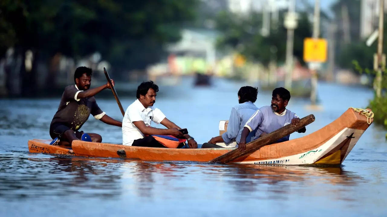 People travel via a boat at the waterlogged DLF residential area after rain at Semmancheri, in Chennai