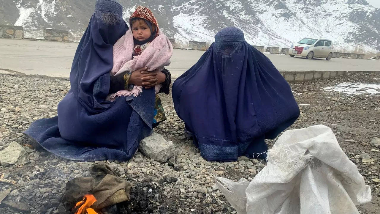Gulnaz has to keep her 18-month-old son warm as she begs on a bitterly cold highway on the road to Kabul. (AP photo)