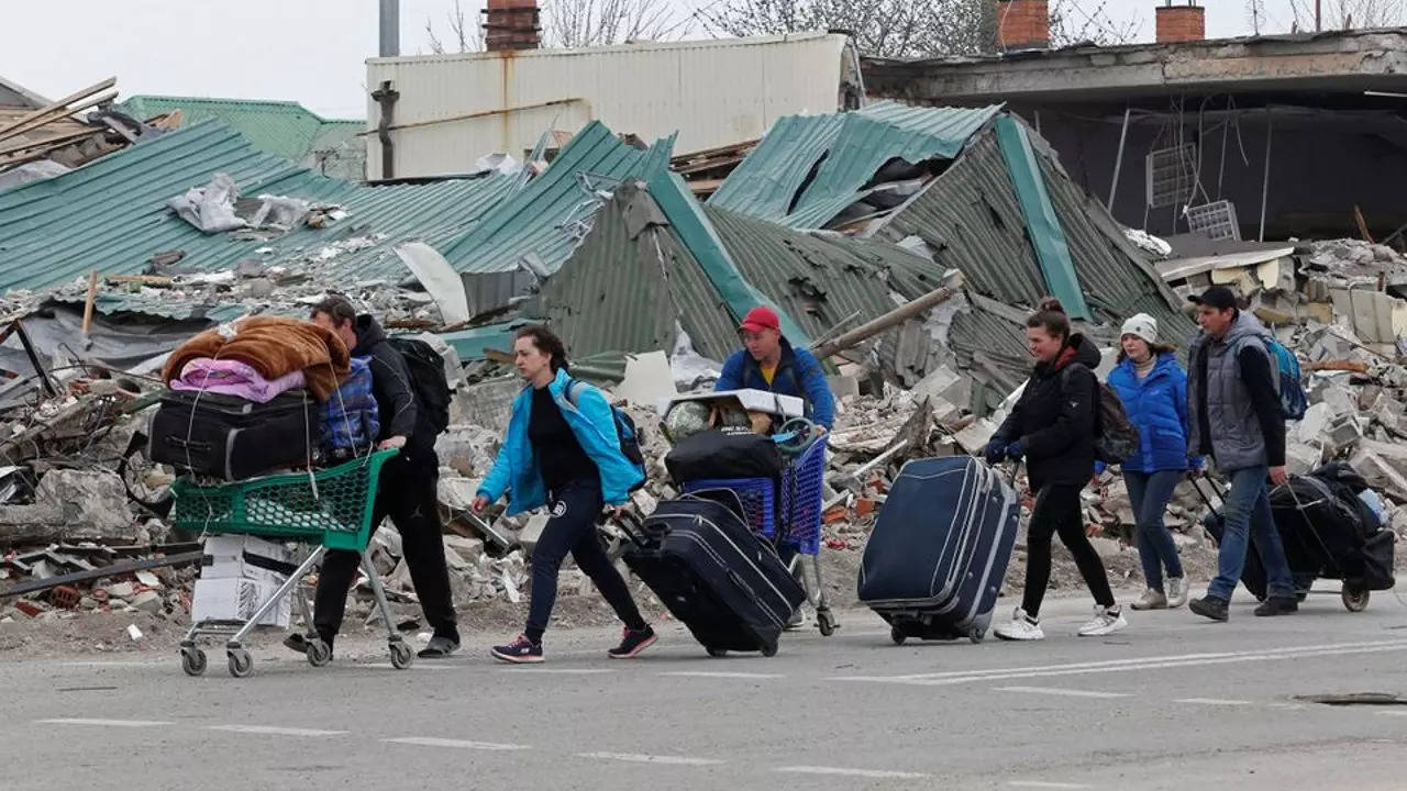 Local residents carry belongings past a building destroyed during Ukraine-Russia conflict in the southern port city of Mariupol, Ukraine.