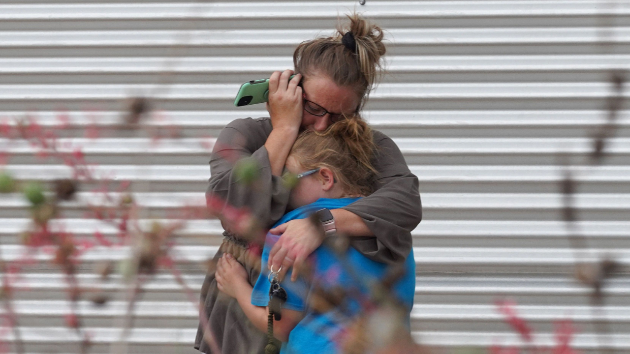 A woman cries and hugs a young girl outside the Willie de Leon Civic Center where grief counseling will be offered in Uvalde, Texas, on May 24, 2022. - A teenage gunman killed 18 young children in a shooting at an elementary school in Texas on Tuesday (AFP)