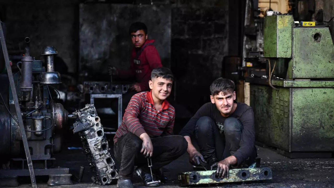 Young Syrian boys work at a machine repair shop, in the town of Jandaris, a day before the annual World Day Against Child Labour. (AFP)