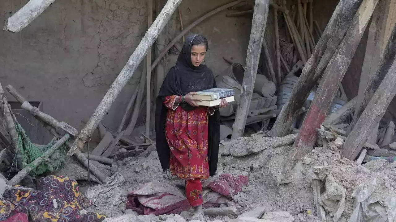Afghan girl salvages belongings from her destroyed house  in Gayan district in Paktika province, Afghanistan. (AP Photo)