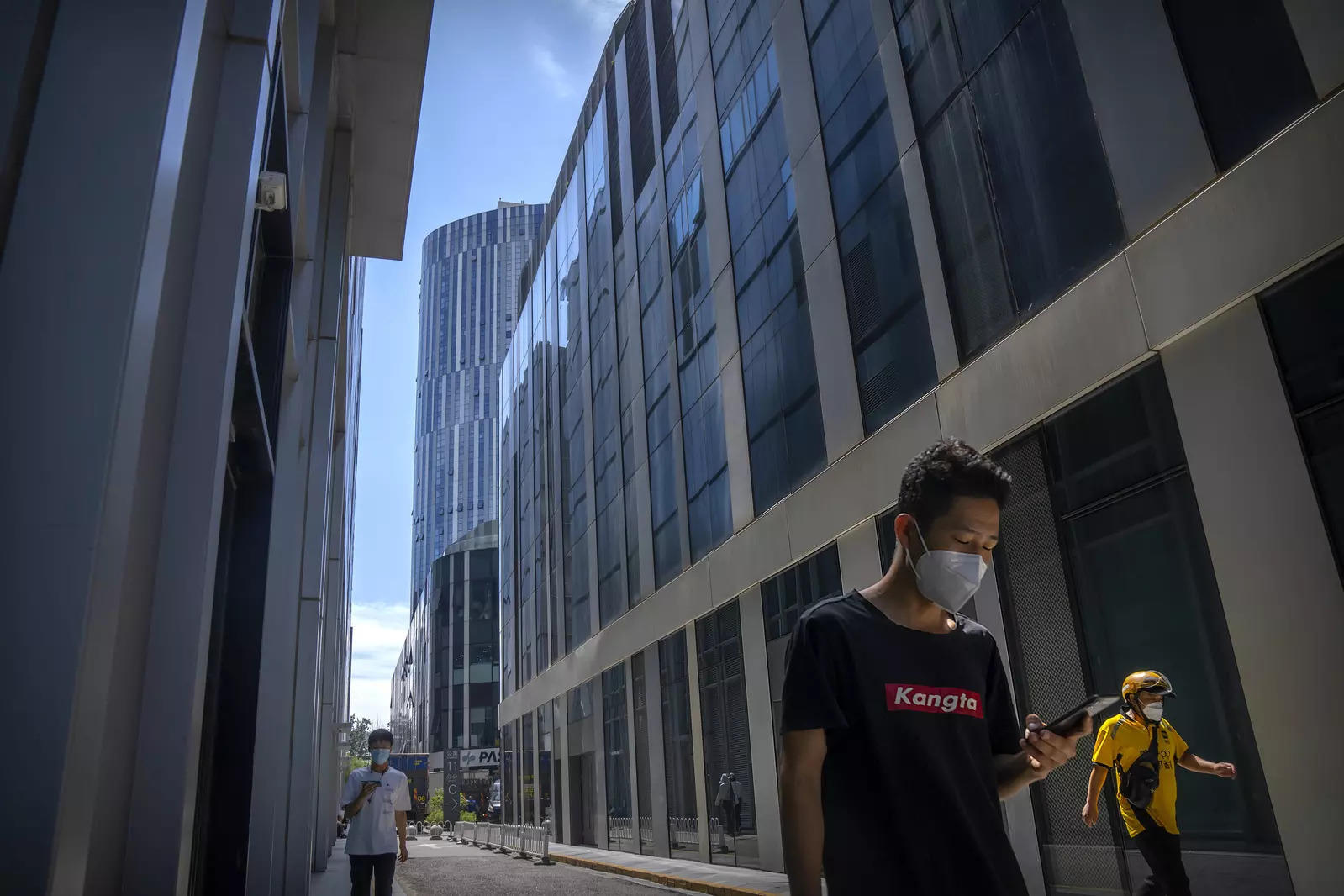Delivery drivers wearing face masks walk through a shopping and office complex in Beijing